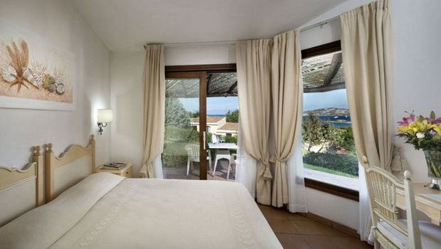 Helles, gemütliches Doppelzimmer mit mediterraner Einrichtung, großen Fenstern und direktem Zugang zur Terrasse – traumhafter Blick auf das Meer und die grüne Umgebung.