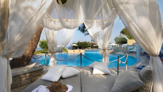 Romantische Daybed-Liege mit weißen Vorhängen direkt am Pool – perfekter Ort zum Entspannen und Träumen unter der mediterranen Sonne mit Blick auf das erfrischende Wasser.