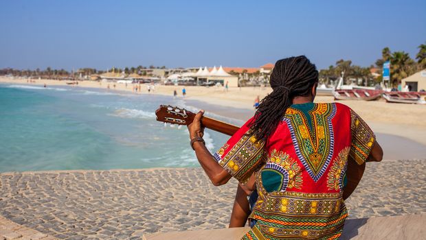 Musician with guitar and rasta hair at Santa Maria Beach, Sal