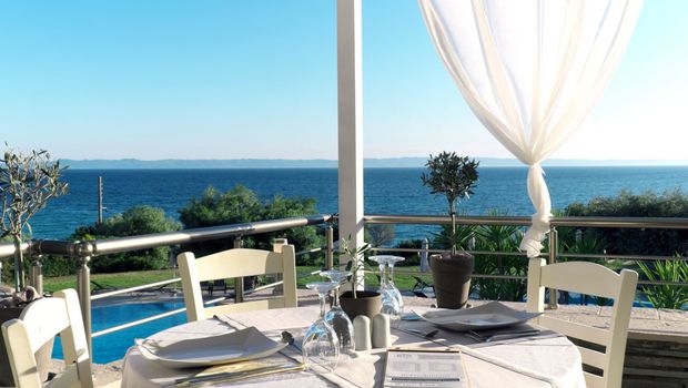 Stilvoll gedeckter Tisch auf einer Terrasse mit traumhaftem Blick über das tiefblaue Meer – ideal für ein entspanntes Mittag- oder Abendessen mit mediterranem Flair.