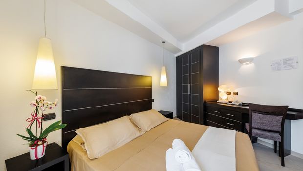 Modern eingerichtetes Doppelzimmer mit warmen Farbtönen, stilvollen Möbeln, Schreibtisch und frischer Orchidee – ideal für entspannte Urlaubstage mit Komfort.