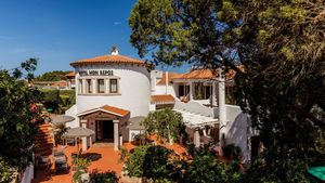 Charmantes Hotel im mediterranen Stil mit weißer Fassade, Terrakottadach und idyllischer Außenterrasse – umgeben von grüner Natur.