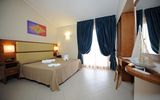 Freundlich eingerichtetes Doppelzimmer mit hellen Farben, gemütlichem Bett und Schreibtisch – ideal zum Entspannen nach einem Urlaubstag.